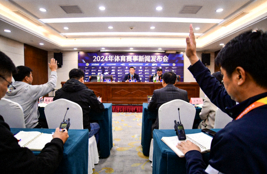 体育媒体发布会现场，记者在台下记录并准备提问
